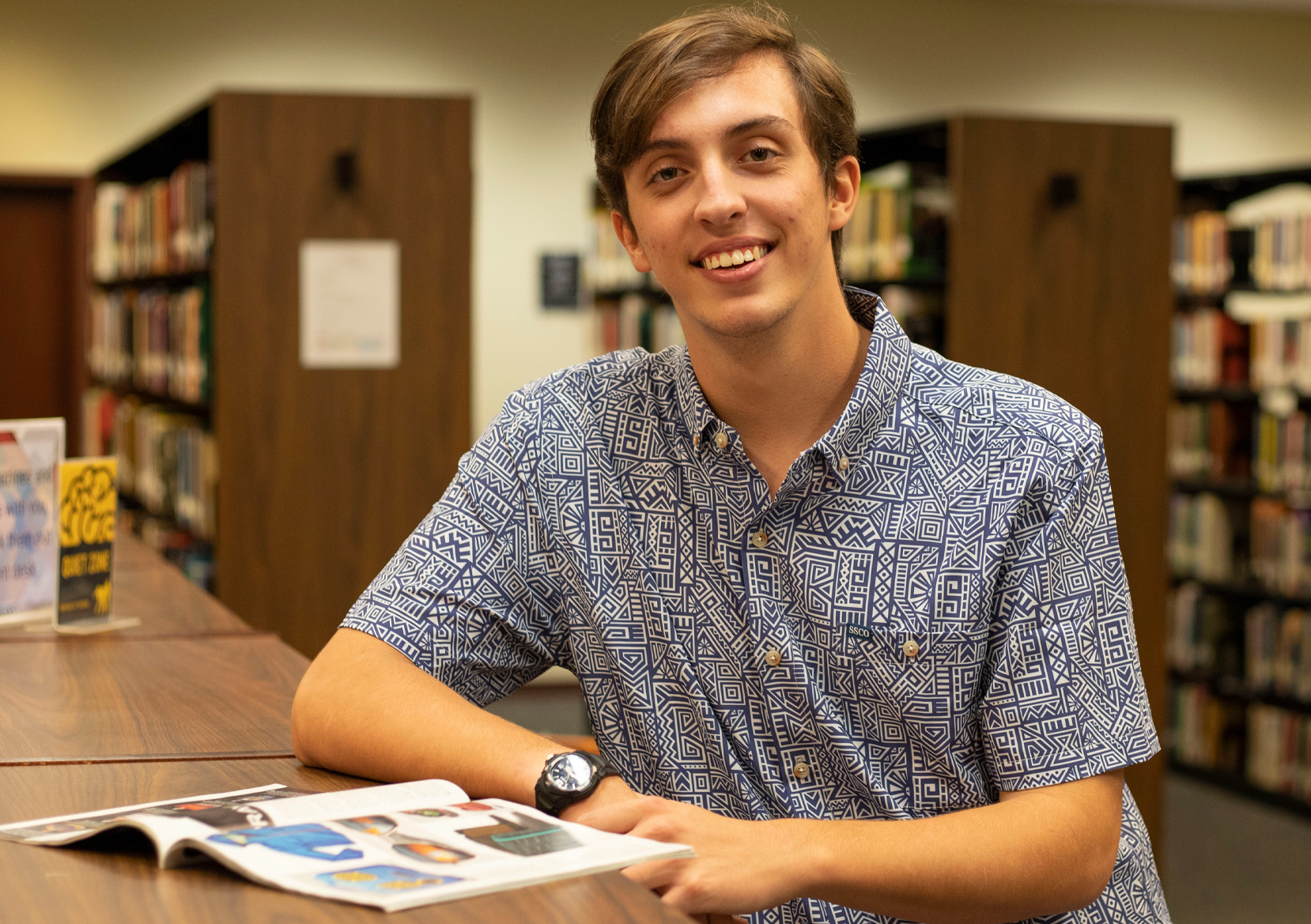 male student in library with book